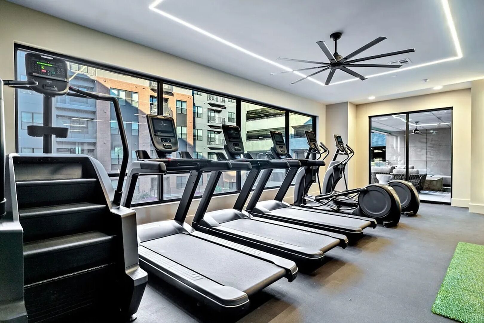 Una palestra moderna con tapis roulant, cyclette e una ventola a soffitto.