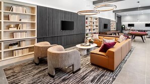 A modern living room with a sofa, armchairs, a coffee table, and bookshelves. - Landing | Incredible 3BD, Pool, Gym (Plano)
