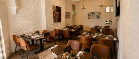 A restaurant with brick walls, wooden tables, and brown leather chairs.