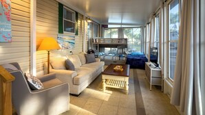 A room with a sofa, a chair, a table, a bunk bed, and a lamp.