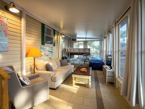 Ein Zimmer mit einer Couch, einem Sessel, einem Tisch, einem Etagenbett und einer Lampe.