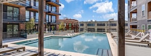 Une piscine sur le toit offrant une vue sur les bâtiments environnants, notamment une construction en briques et un immeuble moderne doté de balcons.