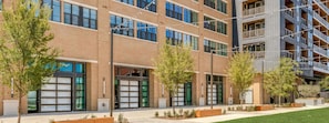 Un immeuble à plusieurs étages doté de grandes fenêtres, d’un espace extérieur aménagé pour s’asseoir et d’une pelouse bien entretenue.