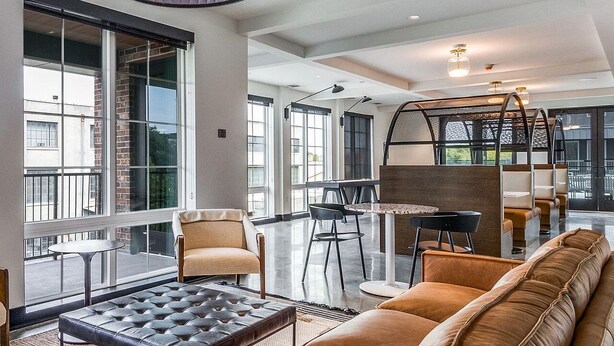 Un intérieur moderne avec de grandes fenêtres, un canapé, des fauteuils et une table.