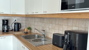Een kleine keuken met een vaatwasser, een koffiezetapparaat, een broodrooster en een magnetron.