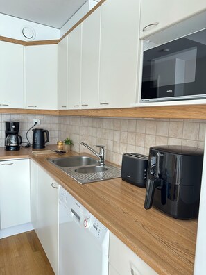 Una cocina compacta equipada con lavavajillas, cafetera, tostadora y microondas.