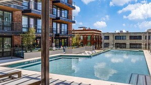 Piscina no terraço com vista para edifícios ao redor, incluindo um prédio de tijolos e um edifício moderno com varandas.