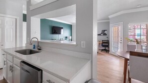 Eine moderne Küche mit Geschirrspüler, doppelter Spüle und einem Essbereich mit Tisch und Stühlen.