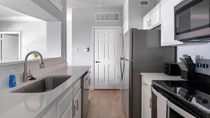 A modern kitchen with a stainless steel refrigerator, a microwave, and a stove. - Landing | Stylish 1BD, Clubhouse (Houston)