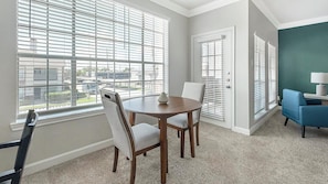 A room with a round table, two chairs, a blue armchair, and a door with a window. - Landing | Modern 1BD, Clubhouse (Houston)