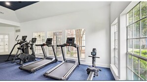 Ein Fitnessraum mit Laufbändern, Fahrrädern und Rudergeräten.