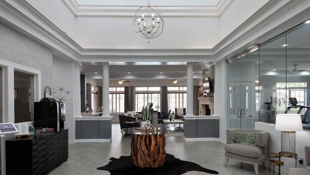 A spacious living area with a modern chandelier, a fireplace, and a large window. - Landing | Incredible 1BD, Gym (McKinney)