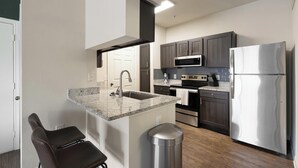 Una cocina moderna con encimeras de granito, electrodomésticos de acero inoxidable y armarios de madera oscura.