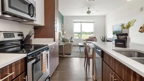Eine moderne Küche mit Mikrowelle, Herd und Spüle. Ein Essbereich mit einer Couch und Blick ins Freie.