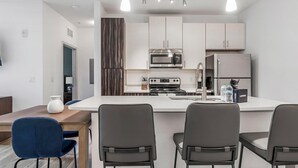 Een moderne keuken met witte kasten, roestvrijstalen apparatuur en een centraal eiland met zitplaatsen.