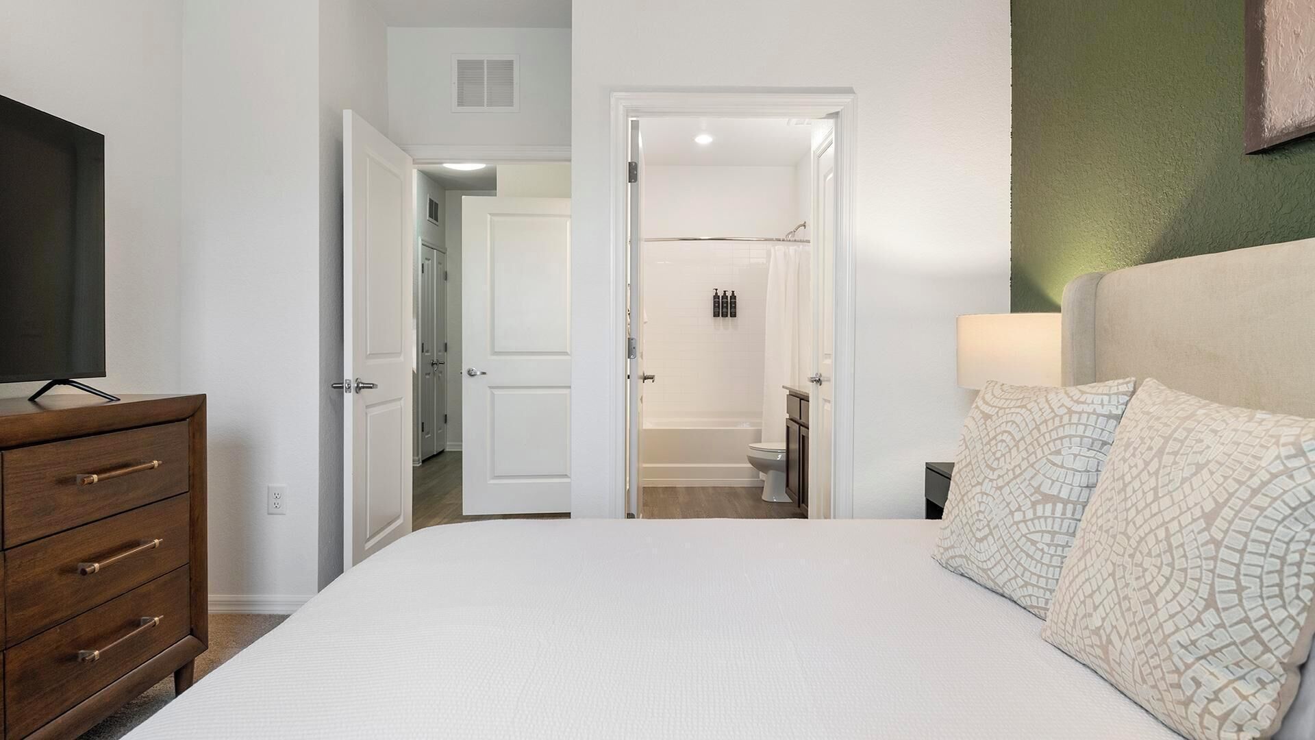 Ein Schlafzimmer mit Bett, Kommode und Fernseher.