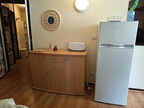 Una cocina con un refrigerador blanco, un armario de madera y una lámpara de pared.