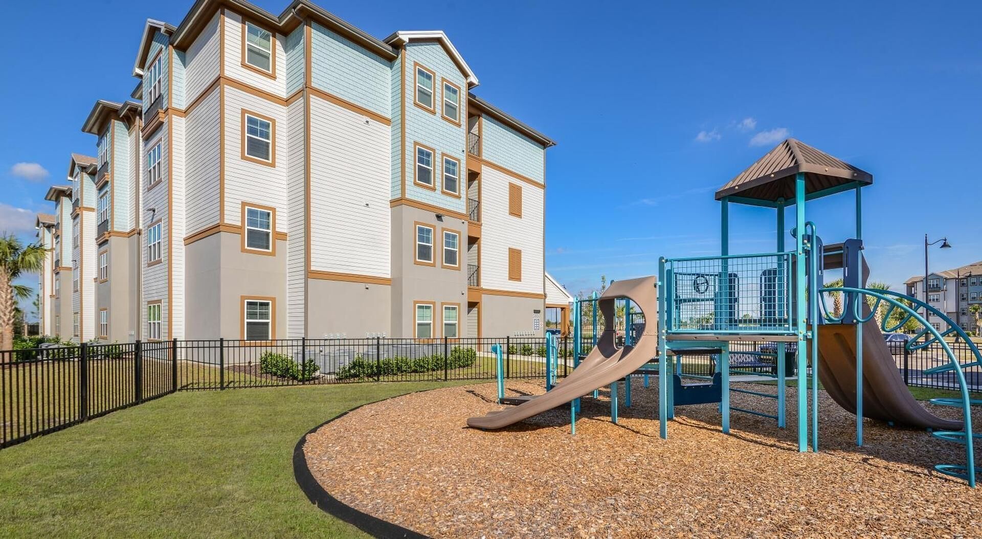 A multi-story residential building with a playground featuring a slide and climbing structures.