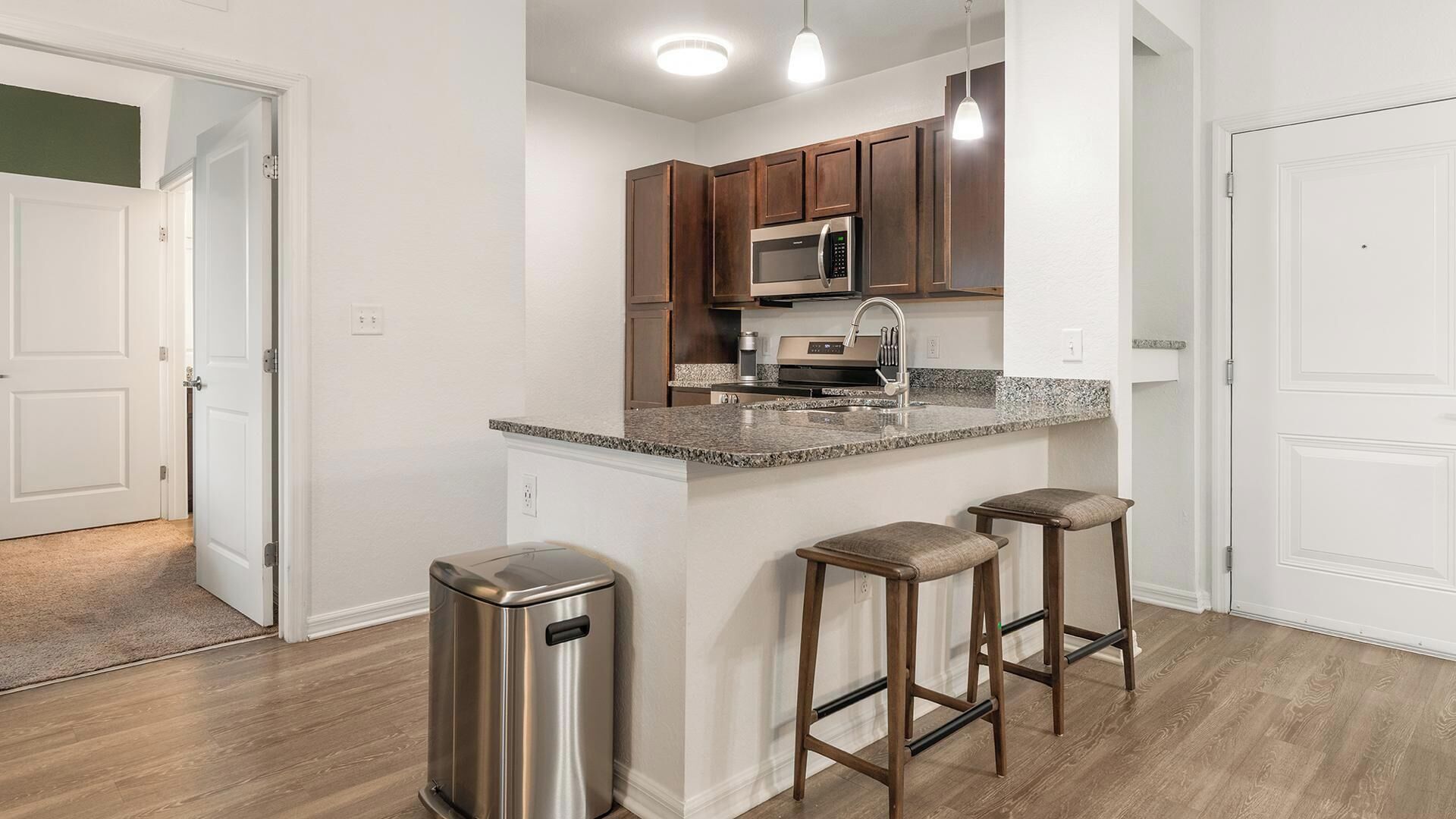 A modern kitchen with a central island, stainless steel appliances, and wooden bar stools.
