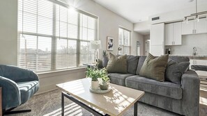 Ein modernes Wohnzimmer mit einem grauen Sofa, einem blauen Sessel und einem Couchtisch mit einer Pflanze.