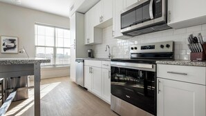 A modern kitchen with white cabinets, a stainless steel range, and an oven. - Landing | Stylish 2BD, Game Room, Gym (Charlotte)