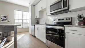 Eine moderne Küche mit weißen Schränken, einem Edelstahlherd und einem Backofen.