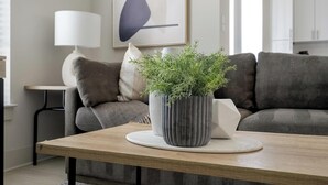 Un saló modern amb un sofà gris, una taula baixa de fusta i una planta en test.
