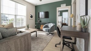 Een moderne woonkamer met een bank, een stoel, een bureau en een televisie.