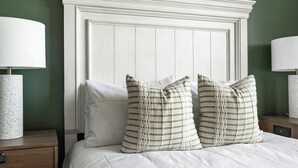 Una cama con ropa de cama blanca, dos mesitas de noche con lámparas y un cabecero.