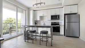 Een moderne keuken met een bar en een balkon met uitzicht, voorzien van roestvrijstalen apparatuur.