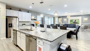 A modern kitchen with a granite countertop, stainless steel appliances, and a dining area with a large TV.