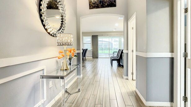 A modern hallway with a clear glass console table, a decorative mirror, and a vase with flowers.