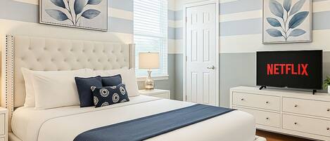 A bedroom with a bed, a TV, a bedside table, and a door.