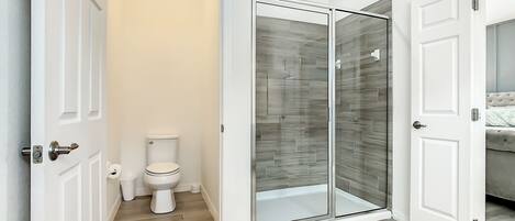 Une salle de bain moderne avec des toilettes, une douche à parois de verre et un plancher en bois.