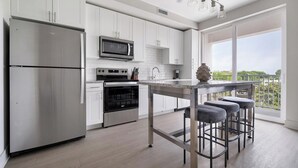Een moderne keuken met roestvrijstalen apparatuur, een granieten aanrecht en een bar met krukken.