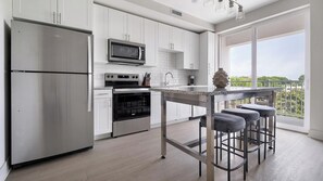 Eine moderne Küche mit Edelstahlgeräten, einer Granitabdeckung und einer Bar mit Barhocker.