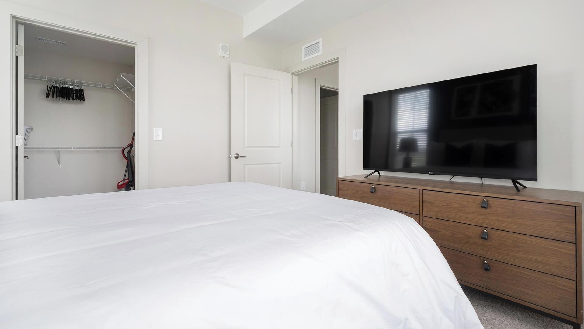 A bedroom with a bed, a TV, a wardrobe, and a closet.