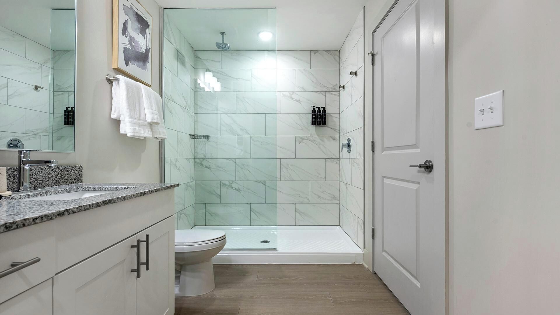 A modern bathroom with a shower, toilet, and vanity.