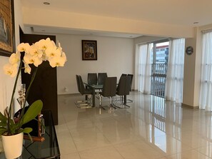 A modern dining area with a glass table and chairs, a potted plant, and a painting on the wall. - Apartment in central area for world cup (Naucalpan de Juárez)