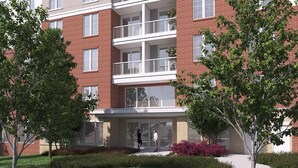Un immeuble en briques à plusieurs étages, doté de balcons, de grandes fenêtres et d’une entrée en verre.