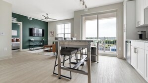 A modern apartment with a kitchen, dining area, and a balcony with a city view. - Landing | Amazing 1BD, Gym, Game Room (Charlotte)