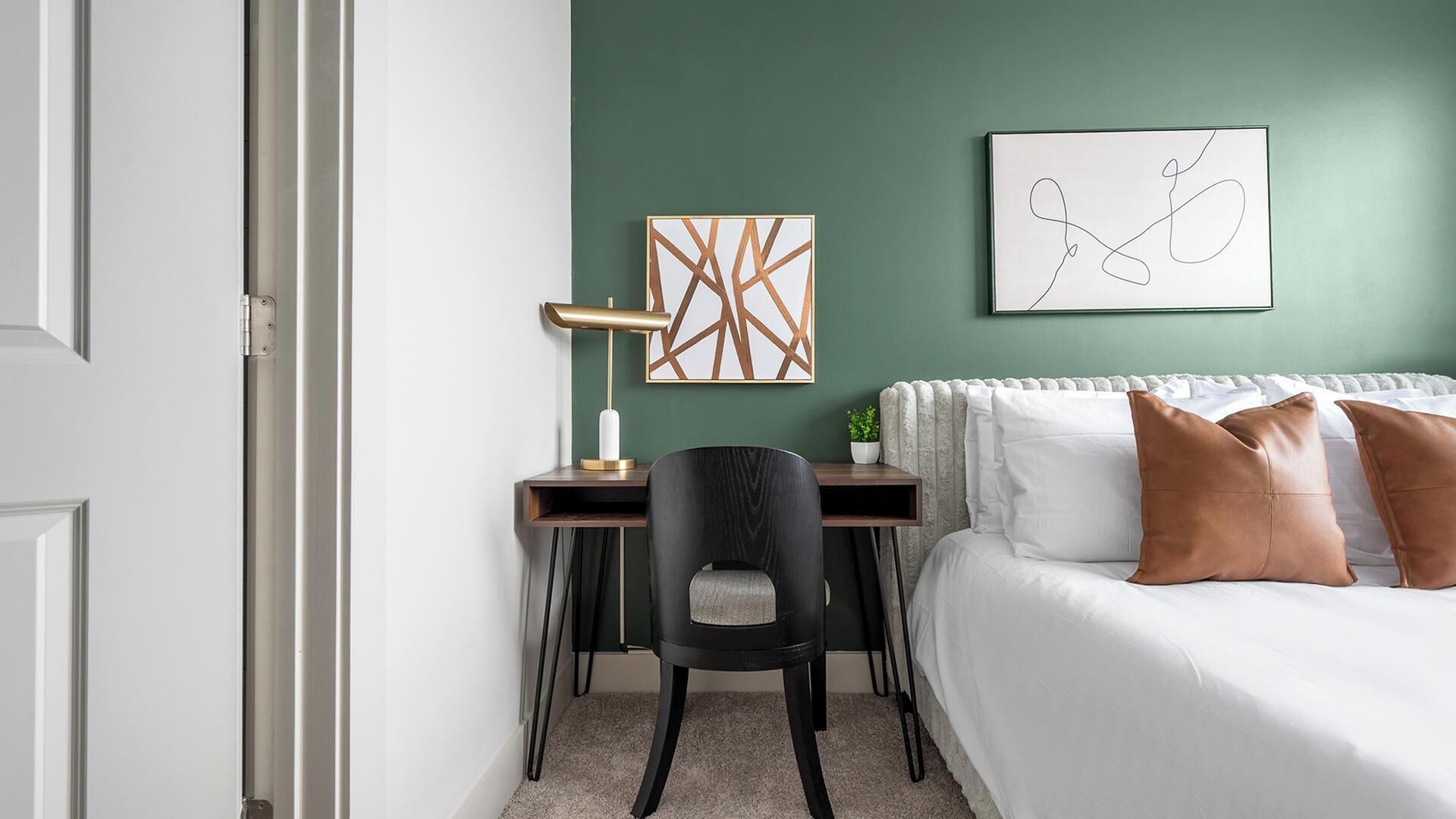 Ein Zimmer mit einem Bett, einem Schreibtisch, einem Stuhl und zwei Bildern an der Wand.