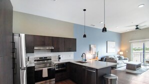 A modern kitchen with dark cabinets, stainless steel appliances, and a large island. - Landing | Beautiful 1BD, Rooftop Lounge, Gym (Springfield)