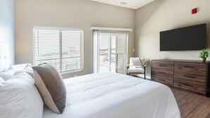 A bedroom with a bed, a chair, a TV, and a dresser. - Landing | Stylish Studio, Pool, Rooftop Lounge (Springfield)