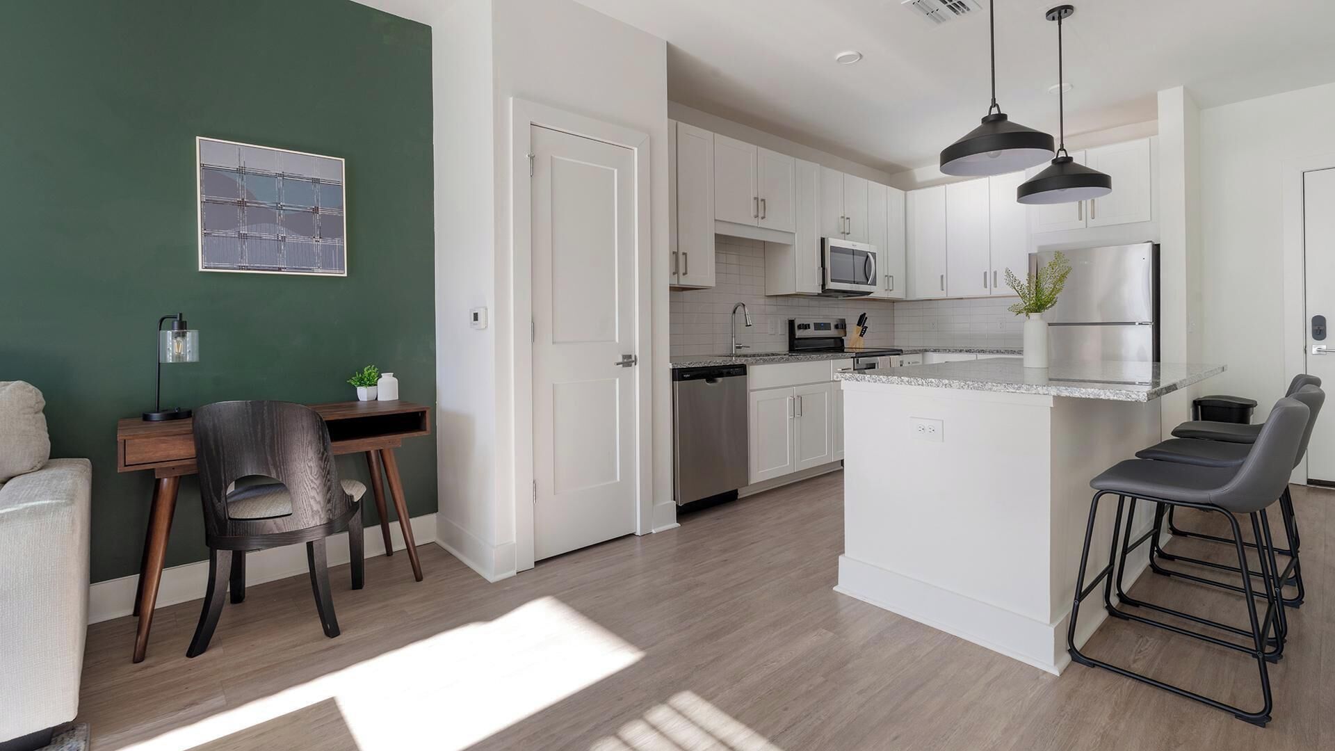 Una cocina moderna con armarios blancos, una isla central y un comedor con una mesa y sillas.