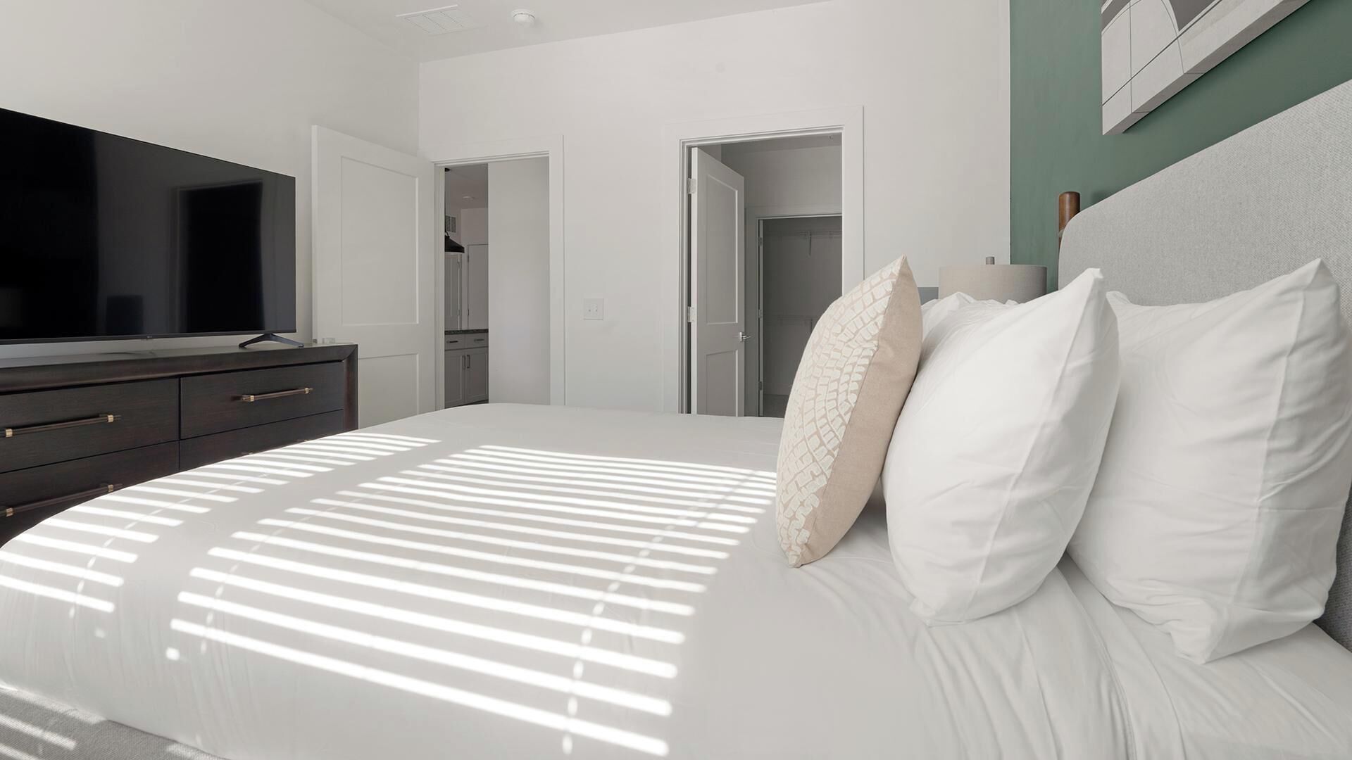 A modern bedroom with a bed, a dresser, and a television.