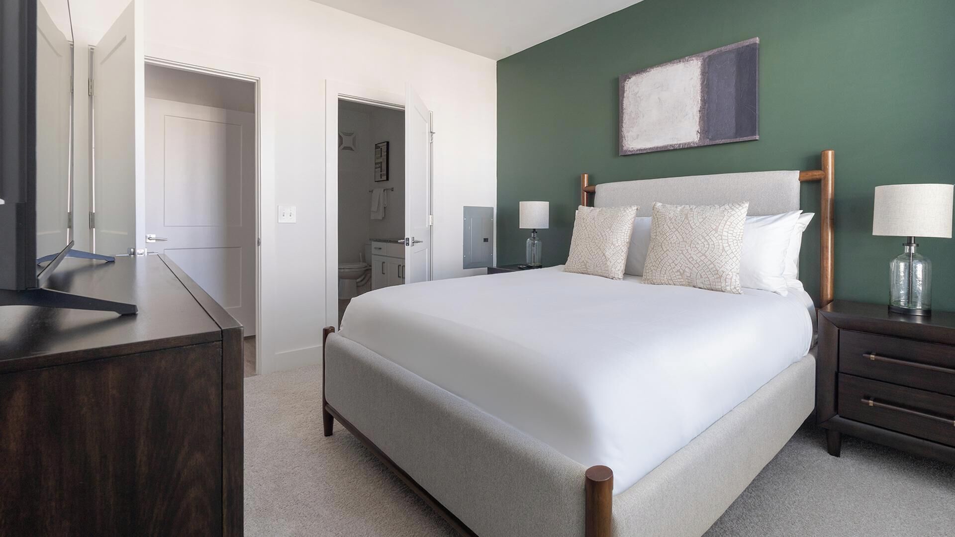 Une chambre à coucher avec un grand lit, des tables de chevet, une commode et un tableau au mur.