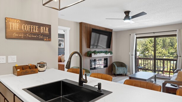 A kitchen with a large island, a coffee bar sign, and a dining area with a table and chairs.