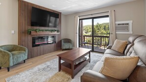 A living room with a flat-screen TV, a sofa, a coffee table, and a fireplace.