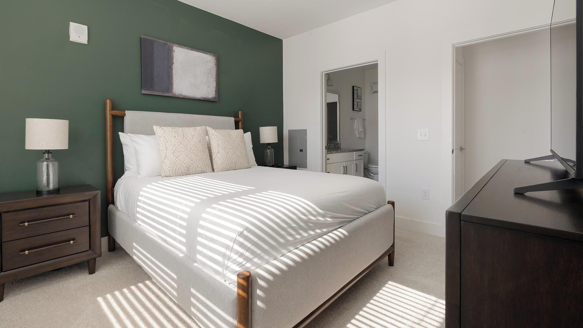 A bedroom with a bed, nightstands, a dresser, and a painting on the wall.